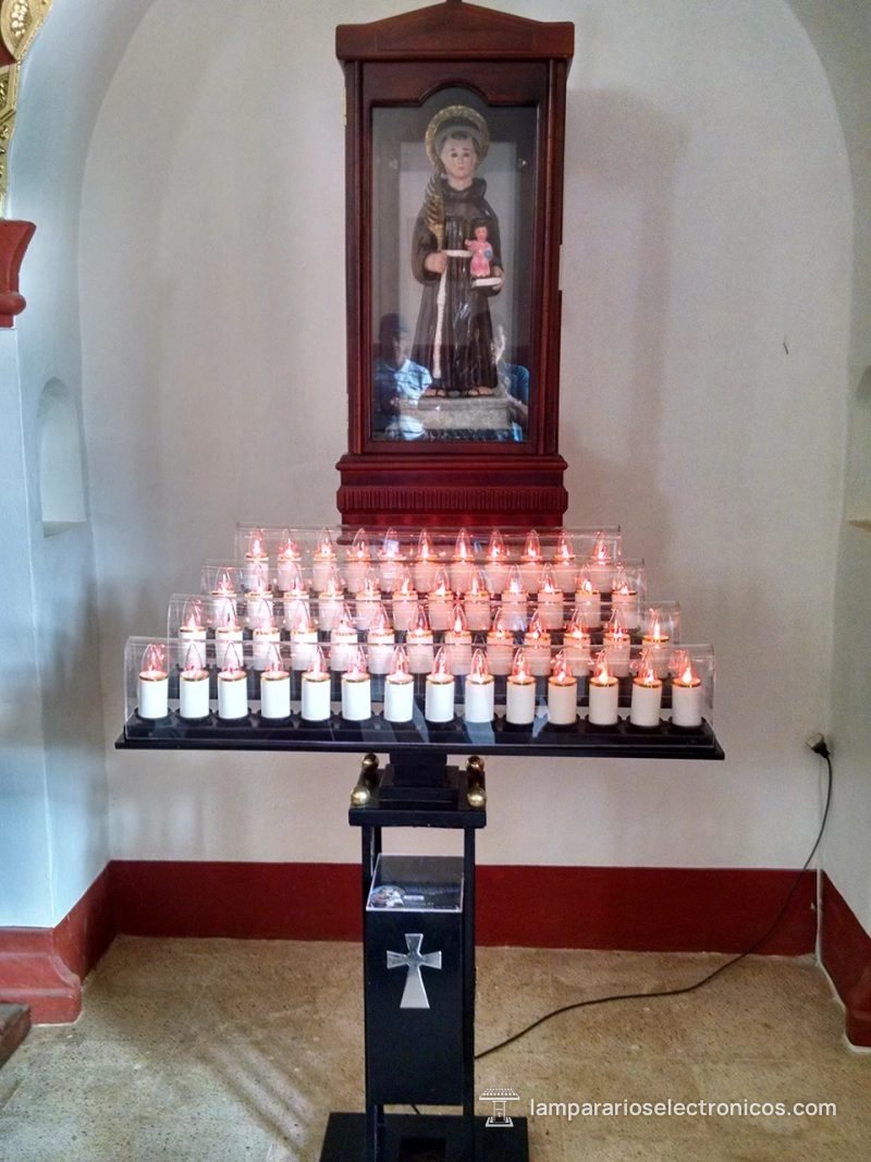 Lamparario electrónico encendido en una capilla lateral, bajo la imagen de un santo